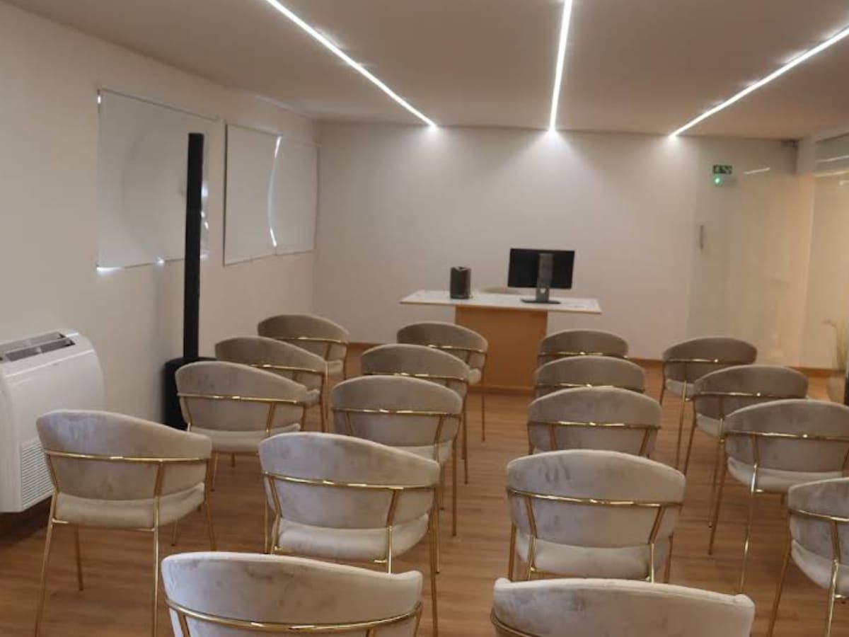 Auditório da AC CLINIC preparado com cadeiras, ecrã e sistema de iluminação.